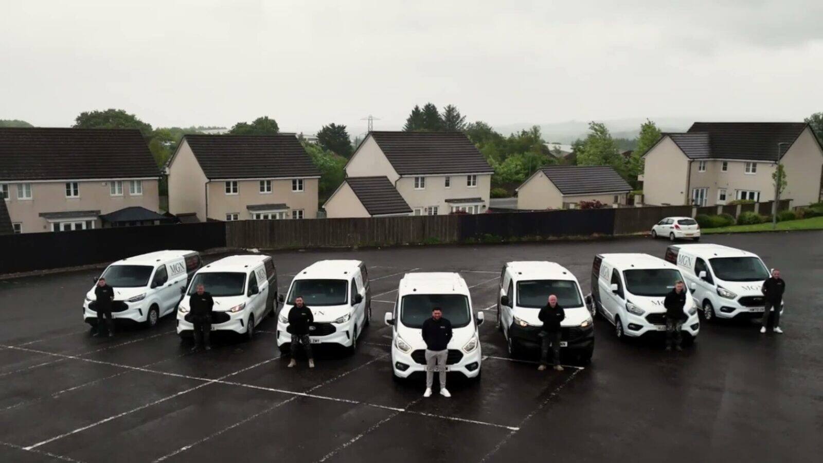 Aerial view of the MGN Group fleet and team outside a residential development